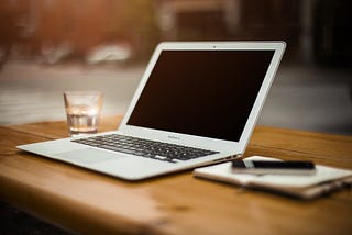 Desk with computer, pen and notebook.