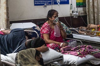 Woman in an hospital using an oxygen mask in India. Image from the BBC.