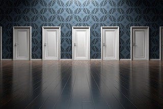 An image of 6 white doors in a corridor