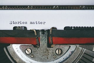 an antique typewriter with a sheet of paper and words that read stories matter