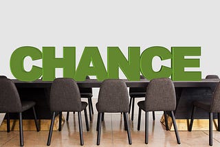 A conference table with empty chairs with ‘CHANCE” writen above