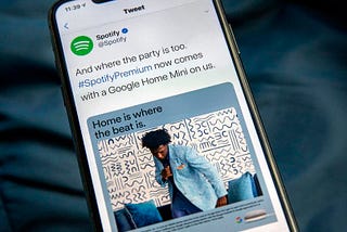 An image of a phone displaying a promoted tweet from Spotify.