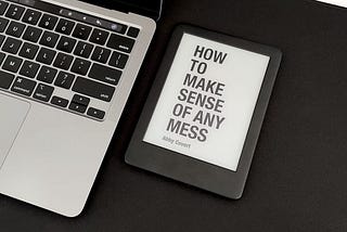 Picture of a kindle next to a computer, with the book How to Make Sense of Any Mess by Abby Covert on the cover.
