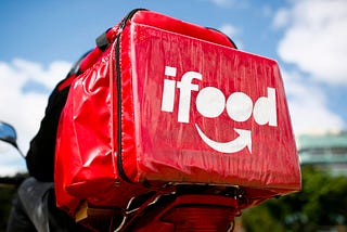 Foto de uma mochila de entrega de comida vermelha com a logo do iFood em branco