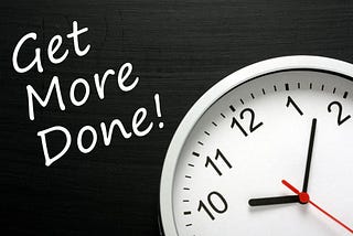 The phrase Get More Done written on a blackboard next to a modern office wall clock.