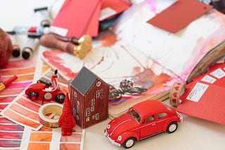 unorganized desk with red car, house, and misc items