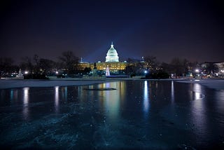 The U.S. Capitol reflecting pool frozen at night.