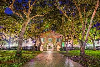 College of Charleston, lit up at night with trees in the background.