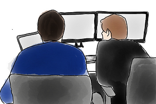 Picture of two software developers sat side by side pairing on some code they are writing