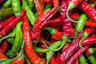 A photograph showing a mixture of red and green chili peppers