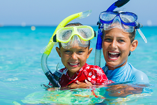 Two boys wearing snorkels and snorkles in the ocean.