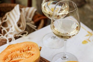 pepene galben tăiat în felii lângă un pahar de vin transparent pe o masă de lemn maro