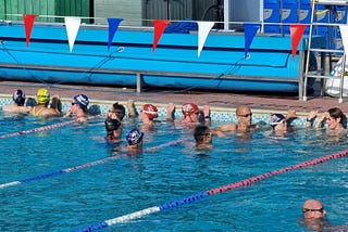 Swimmers in the water in an outdoor pool waiting to start swimming