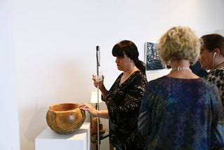 Dr. Cheryl Fogle-Hatch touching “White Ash Burl Bowl with Bark On” carved by George Wurtzel in 2019. Photo by Christine Qabar