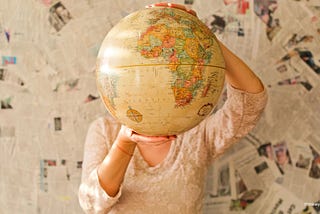 Woman holds world globe in front of face