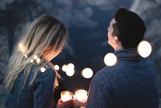 Man and woman talking under string lights outside