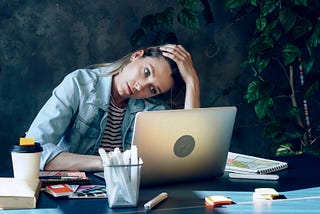 Woman with a laptop appears overworked and stressed out