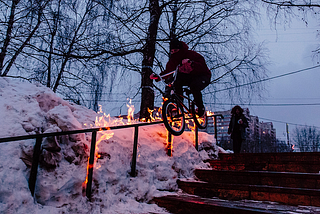 Cyclist freestyling on an outdoor handrail set aflame
