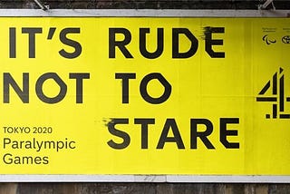 A bright yellow billboard with the words ‘IT’S RUDE NOT TO STARE’ in large black font and the channel 4 logo in black to the right of that text. In the bottom left of the advertisement the words ‘Tokyo 2020 Paralympic games’ are written in smaller black font