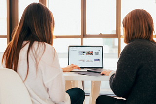 Two women looking at a computer discussing a new consulting project