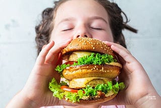 Person about tobite into an enormous hamburger