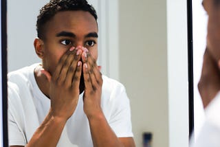 man in white button up shirt covering his mouth