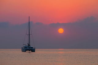 A sailboat in the water at sunset.