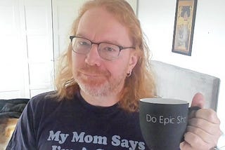 Chris Heilmann wearing a T-Shirt saying “My Mom says I’m a catch” and holding a cup saying “Do Epic Shit”