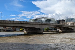 Blue sky with clouds, a plain arched bridge and flowing brown river water