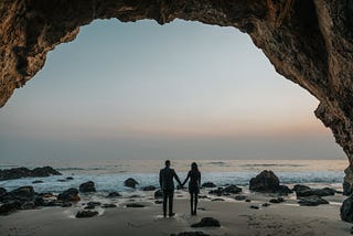 man and woman in silouette facing the beach from the perspective of someone standing behind them, modern marriage