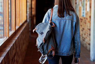 A woman carrying a backpack down a hallway.
