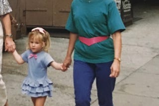 Photo of author and her 3 year old daughter. I’m wearing 80’s fashion from head to toe including purple leggings, a green teen shirt with shoulder pads, of course, Reebok sneakers and slouchy white socks.