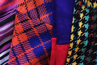 Four sweaters with crazy patterns and different colors such as pink, orange, yellow, red, blue, purple, and black.