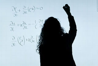 A silhouette of a person writing maths formulae on a white board