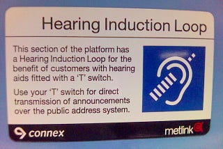 A sign in a train station advising travellers that the public announcement system broadcasts with a hearing induction loop, to allow travellers with a hearing aid to tune into announcements directly with their hearing aid’s receiver. Courtesy Wikimedia commons user avlxyz.