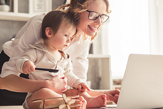 Mom Holding Son While Looking At Laptop