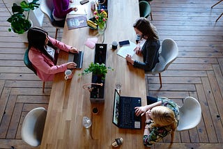 Three women working at long wooden table