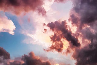 pink and gray cloudy sky covering the yellow sun