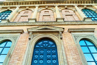Entrance to Munich’s Altes Pinakothek Art Museum — a red stone facade and huge green door