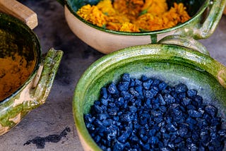Green ceramic bowls containing raw indigo and marigold for dyes