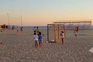 People standing on the beach in Nazaré at sunset