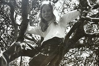 Black and white photo of Tara Brown as a young child climbing a tree.