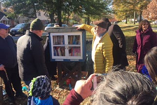 Little library book cabinet at Judson and Lindell, surrounded by community members