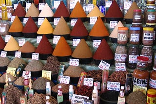 A lovely display of spices in a market, where various spices are in a conical pile along with their prices.