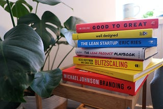 Collection of product management and design books with gorgeous monstera plant.