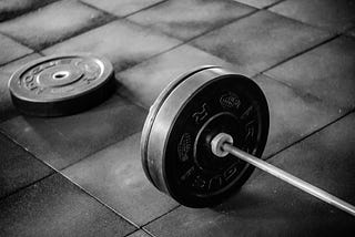 Olympic bar with bumper plates set on the ground in a gym setting.