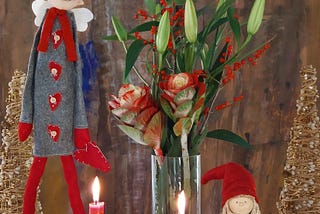 Christmas decoration with flowers in a vase, candles and other dolls.