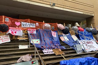 Pro-Palestine posters, blue tarps, and fencing in front of the Portland State University library that was occupied by pro-Palestine activists.