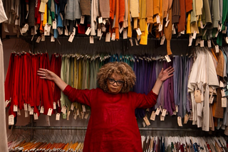 Ruth Carter leaning against a backdrop of colorful costumes on racks