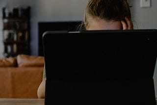 A child sits behind a computer screen.